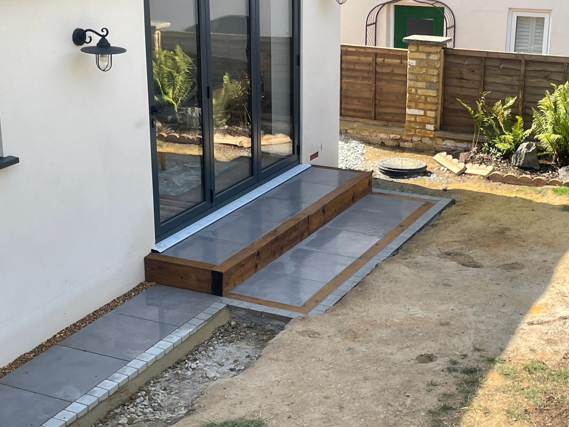 Rear garden transformation with new porcelain patio, returfed lawn, and planted borders.