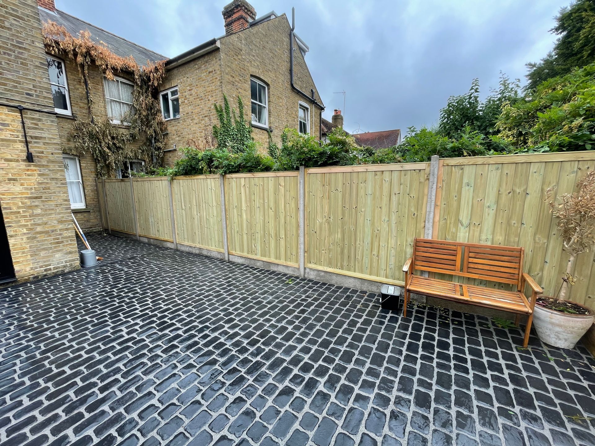 Full rear garden redesign with patio, water feature, new lawn, and planted borders.